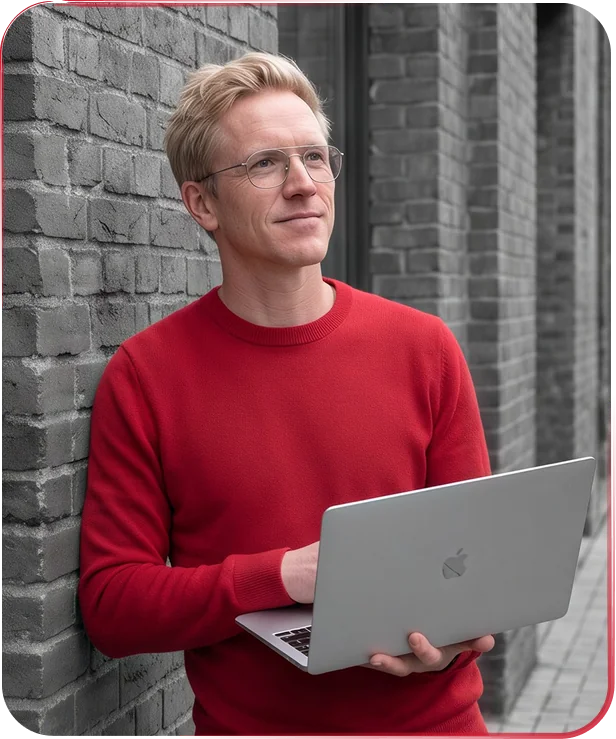 MR HARRY® in a red jumper with a laptop, leaning against a brick wall